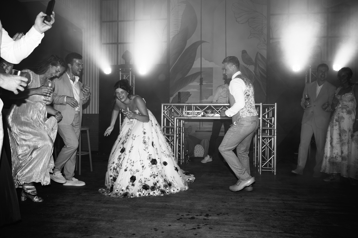 Nina en Kevin dansen op hun bruiloftsfeest, met de DJ-booth op de achtergrond